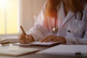 Médica escrevendo em caderno