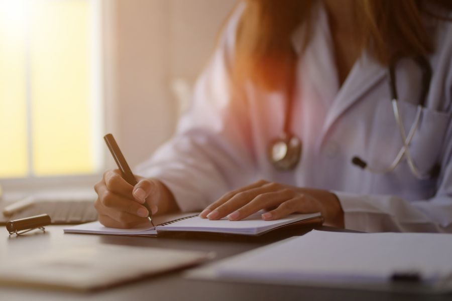 Médica escrevendo em caderno