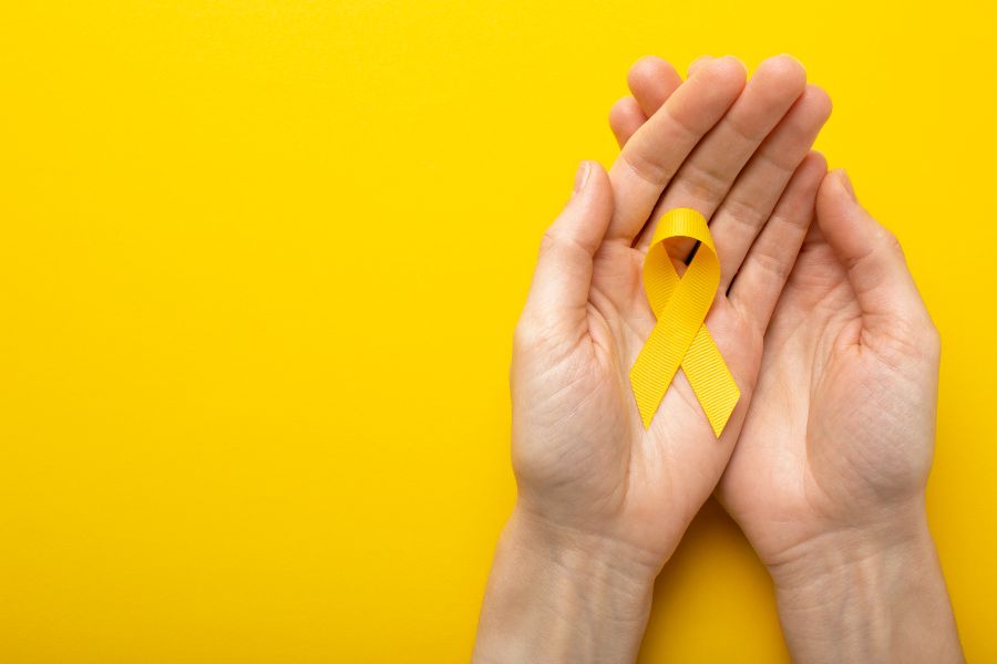 Mãos segurando laço amarelo