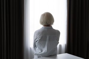 Idosa de costas olhando pela janela